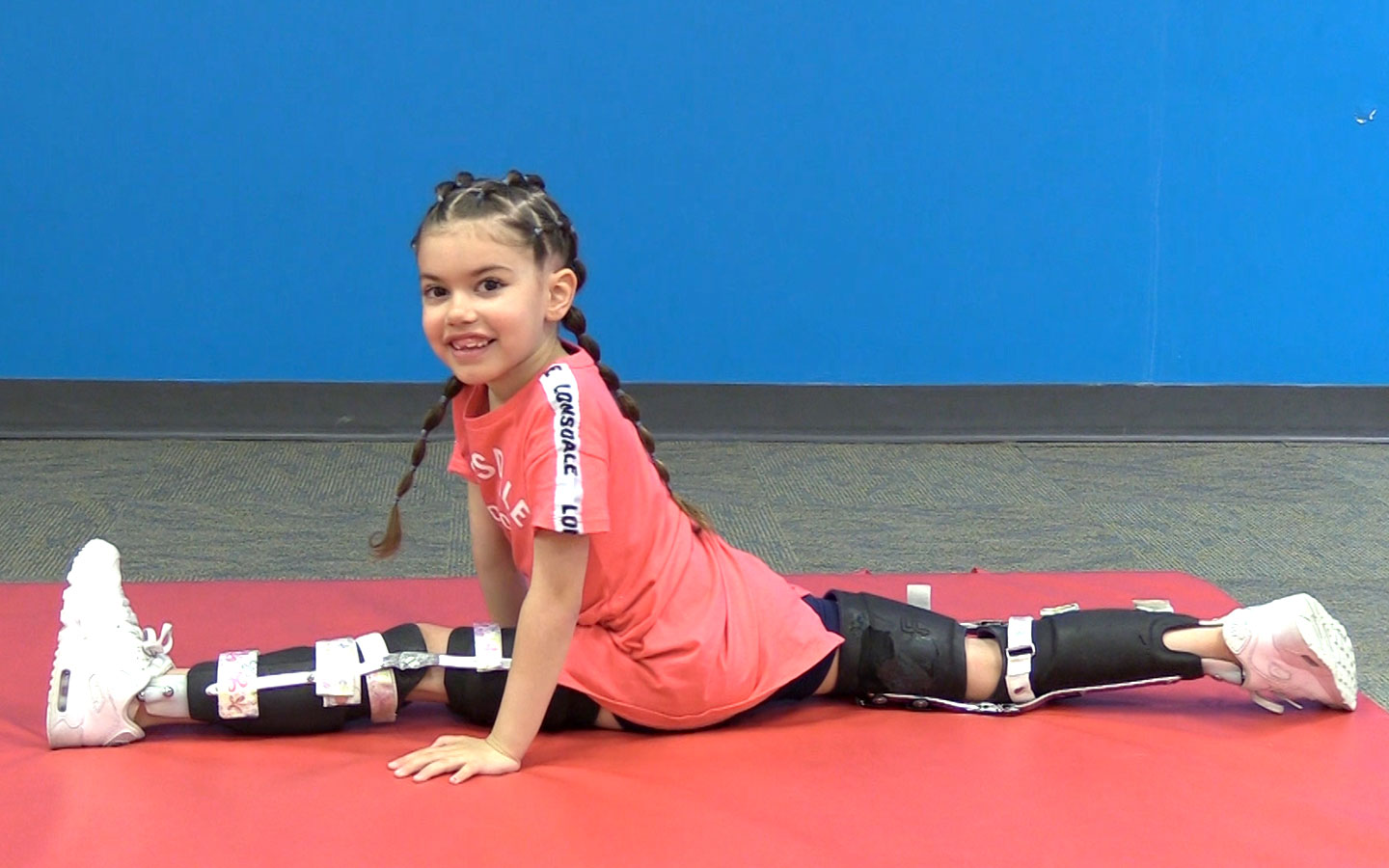 Novita Kid Tiffany wearing her leg braced and doing the splits.