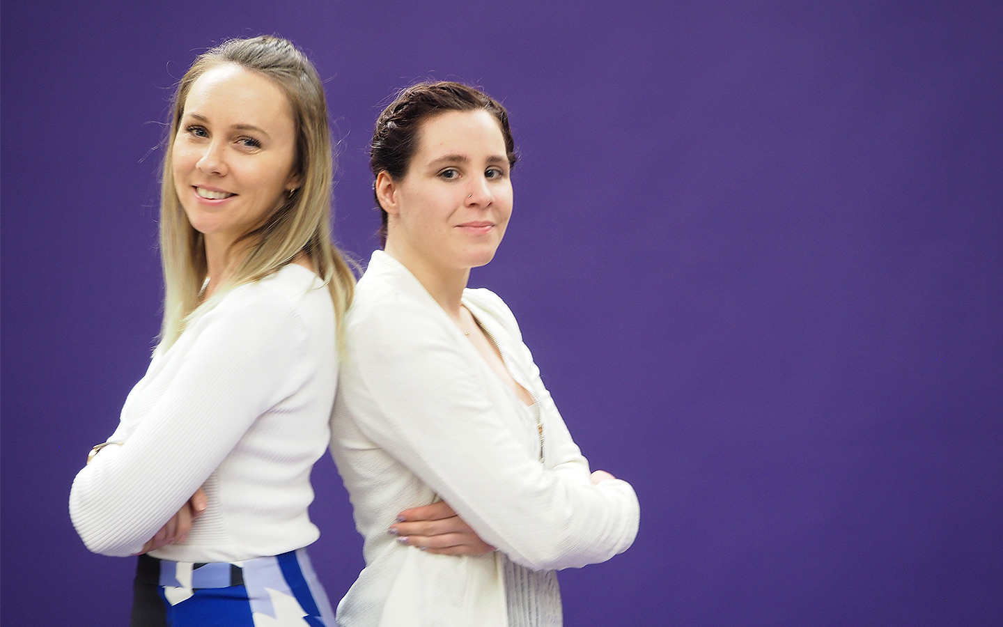 Two women standing in front of a purple background