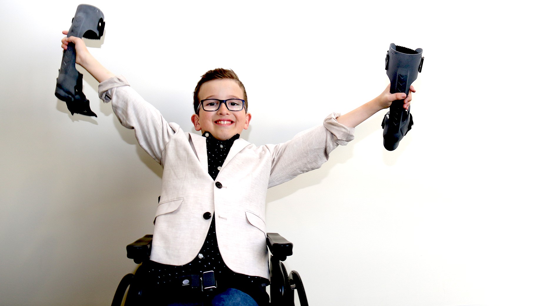 Young boy holding an orthotic in each hand